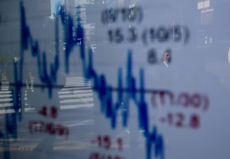 FILE PHOTO : A man is reflected on an electronic board showing a graph analyzing recent change of Nikkei stock index outside a brokerage in Tokyo