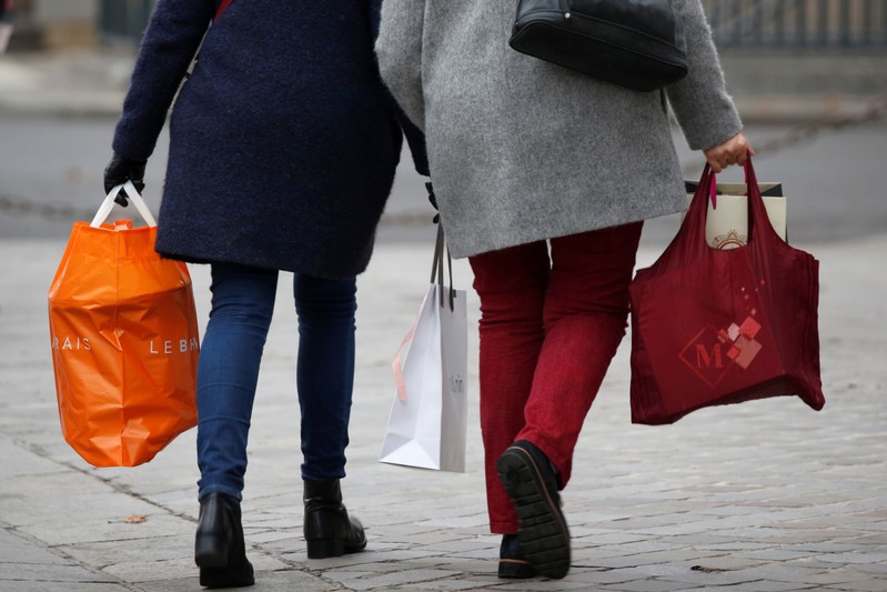 Shoppers walk with shopping bags as they take care of their last-minute Christmas holiday gift purchases outside department stores in Paris