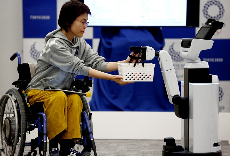 Toyota's Human Support Robot delivers a basket to a woman in a wheelchair at a demonstration of Tokyo 2020 Robot Project for Tokyo 2020 Olympic Games in Tokyo