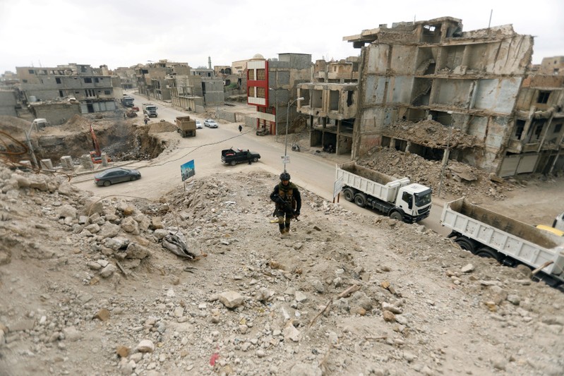 FILE PHOTO: A member of the Iraqi security forces passed by bridges destroyed in the war with Islamic State, in the Old City of Mosu