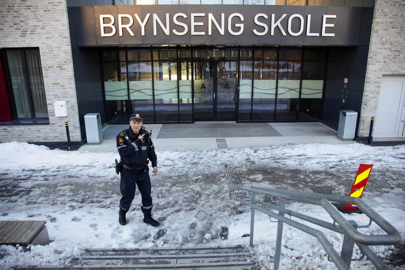 A policeman gestures outside Brynseng School after an attacker armed with a knife injured a teacher and three other staff, in Oslo