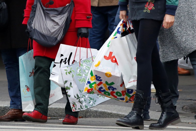 Shoppers carry shopping bags as they take care of their last-minute Christmas holiday gift purchases outside department stores in Paris