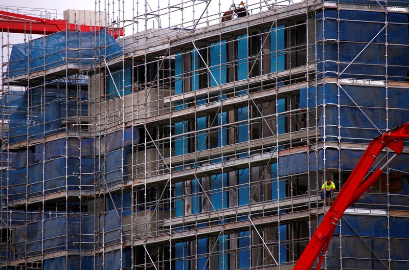 FILE PHOTO: A worker stands on scaffolding at a construction site for a new residential complex in Sydney