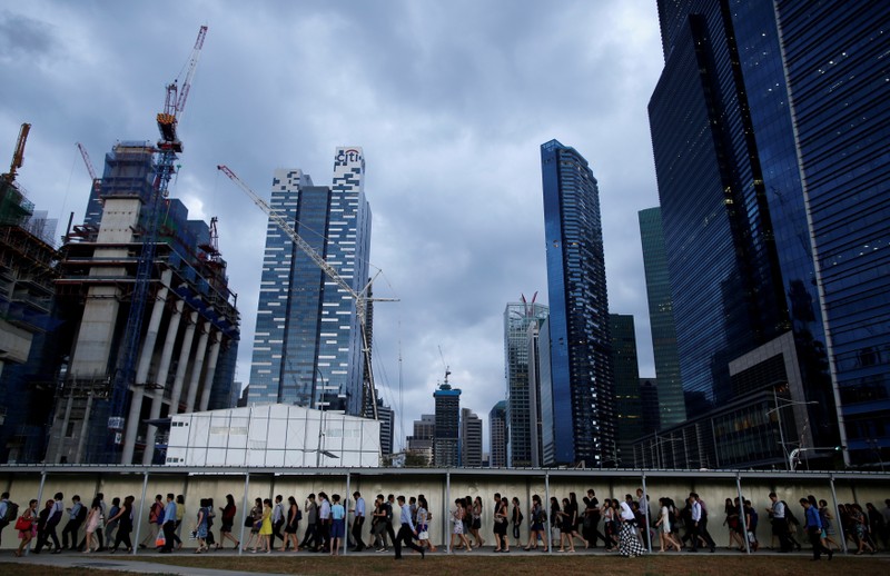 Office workers walk to the train station during evening rush hour in the financial district of Singapore