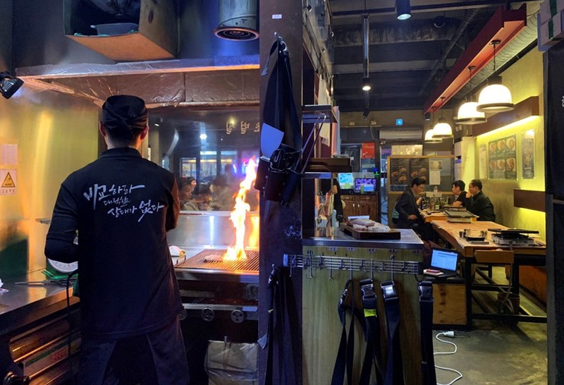 An employee roasts pork at a Korean BBQ restaurant in Seoul