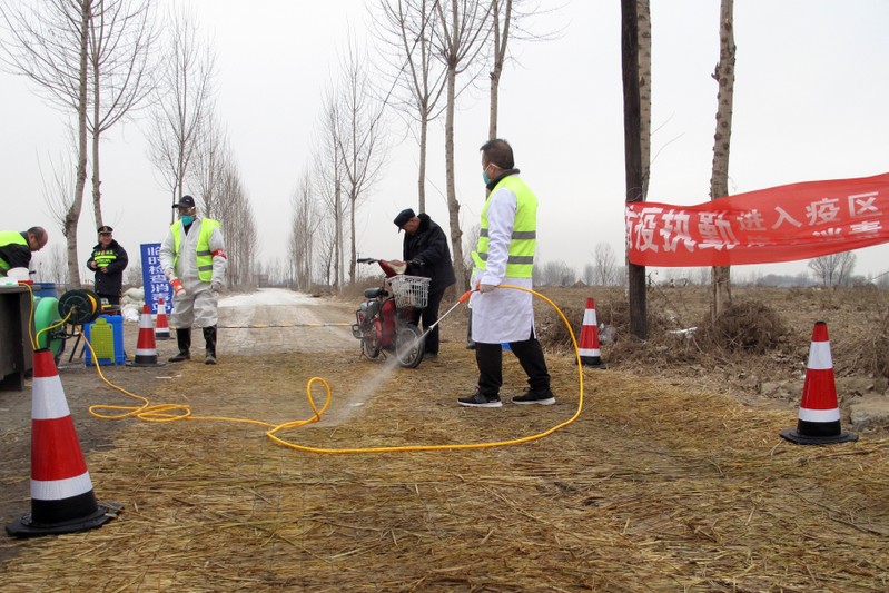 Police officers and workers in protective suits are seen at a checkpoint on a road leading to a farm owned by Hebei Dawu Group where African swine fever was detected, in Xushui