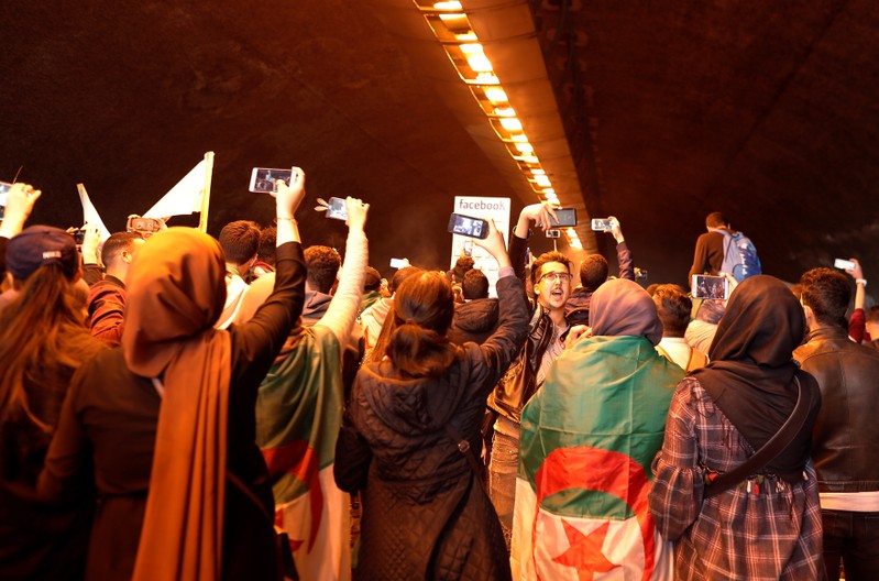 Students use their mobile phones during a protest calling on President Abdelaziz Bouteflika to quit, in Algiers