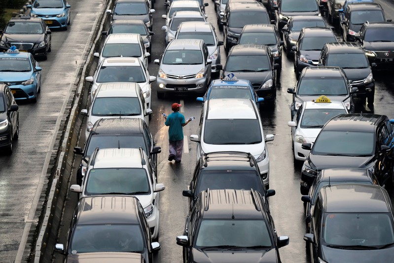 A vendor sells drinking water to motorists in traffic along the Sudirman business district in Jakarta