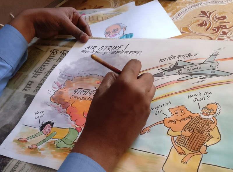 Ganesh Bhalerao, a cartoonist, draws a political cartoon inside his home in Pune