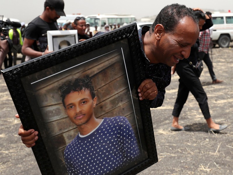 A relative carries a portrait photograph of Ethiopian Airlines pilot Yared Getachew as he mourns at the scene of the Ethiopian Airlines Flight ET 302 plane crash, near the town Bishoftu