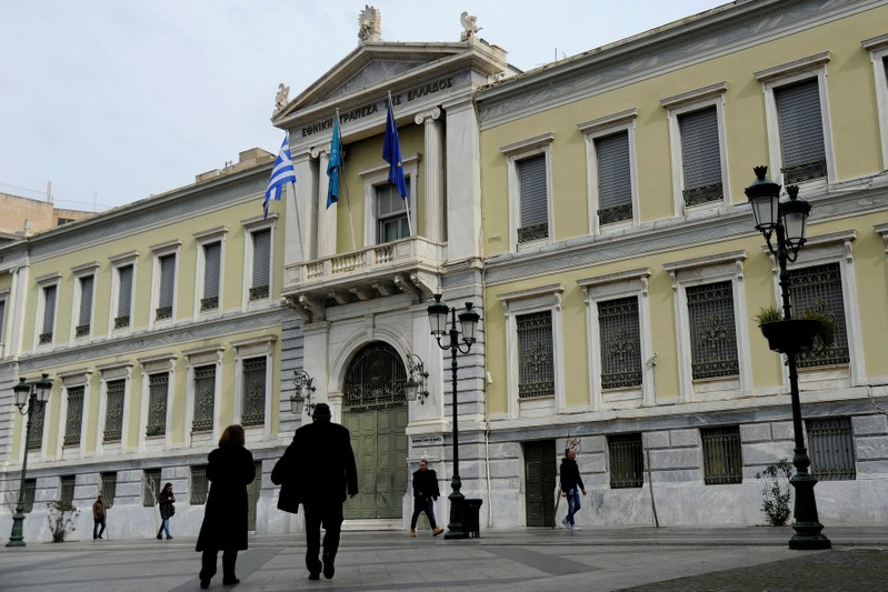 People make their way past the National Bank of Greece headquarters in central Athens