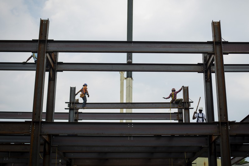 Iron workers install steel beams during a hot summer day in New York