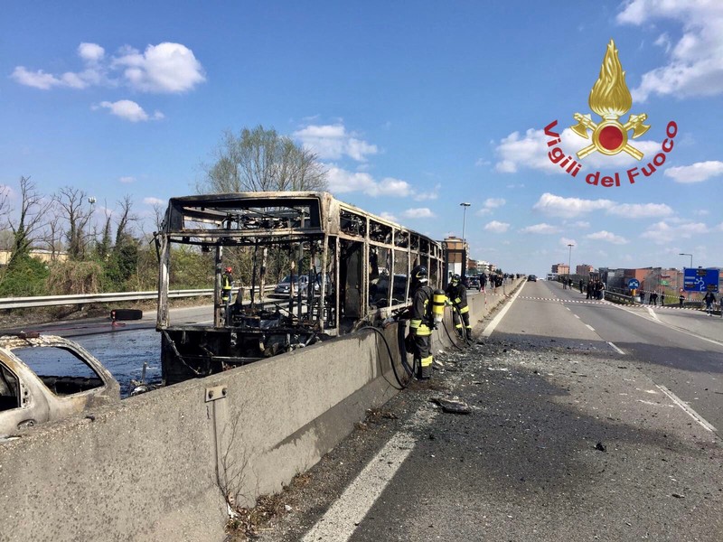 The wrecakge of a burnt out bus is seen on a road in Milan