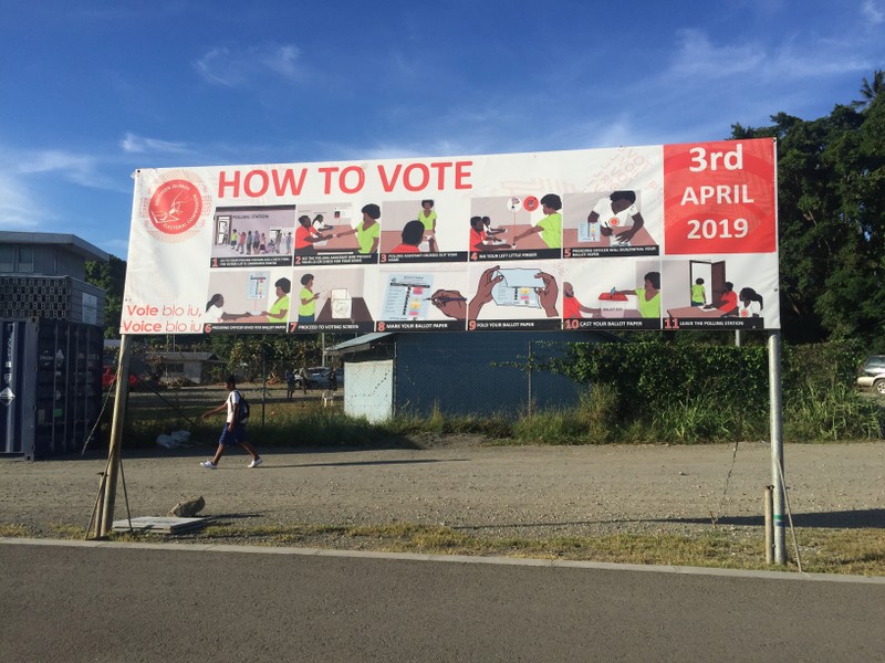 A boy walks past a sign with voting instructions on his way to school in Honiara