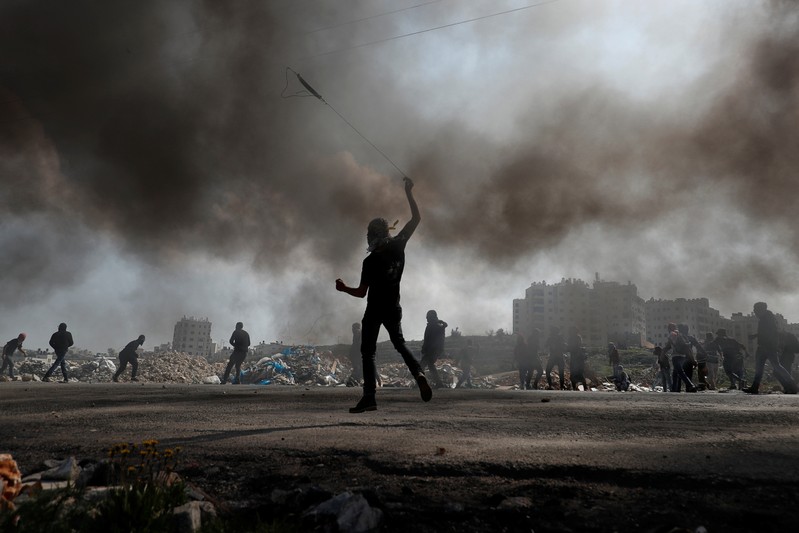 Palestinian protesters hurl stones at Israeli troops during clashes near the Jewish settlement of Beit El, in the Israeli-occupied West Bank