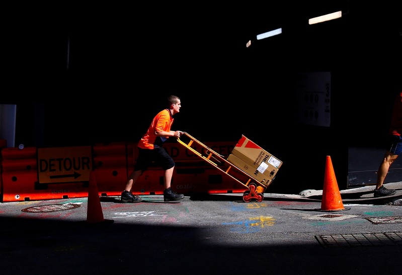 FILE PHOTO: A worker pushes a trolley loaded with goods past a construction site in the central business district of Sydney