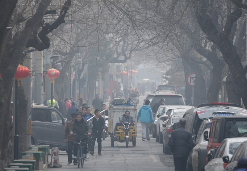 People are seen in a traditional alleyway on a polluted day in central Beijing