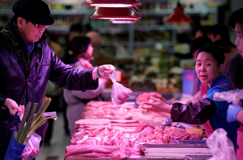FILE PHOTO: A resident gets pork from a vendor at a market in Beijing