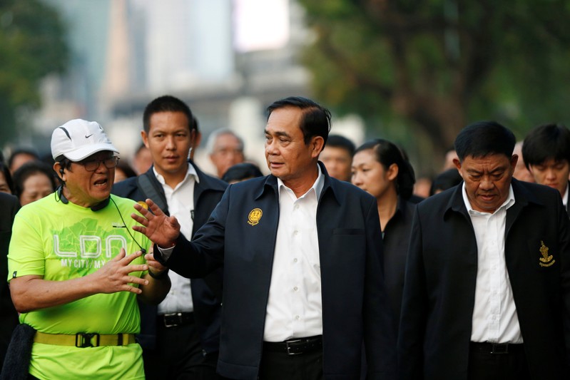 Thailand's Prime Minister Prayut Chan-o-cha talks with a man as he visits Lumphini Park ahead of the general election, in Bangkok