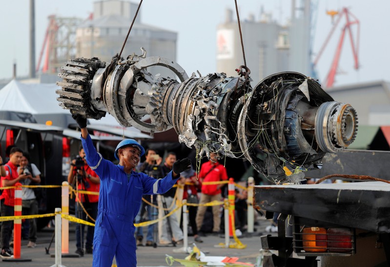 A worker assists his colleague as an turbine engine of Lion Air flight JT610 is lifted up at Tanjung Priok port in Jakarta