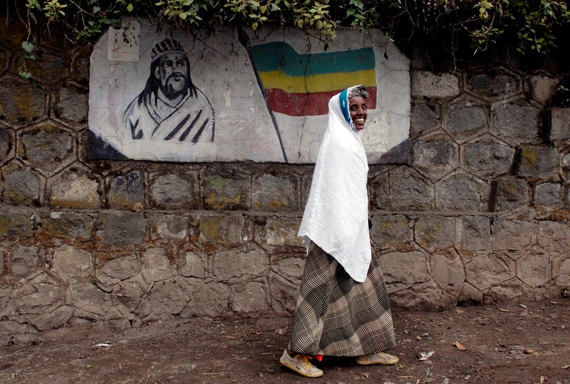FILE PHOTO: A traditionally-dressed Ethiopian woman walks past a mural depicting Ethiopia's Emperor Tewodros II in Addis Ababa, Ethiopia