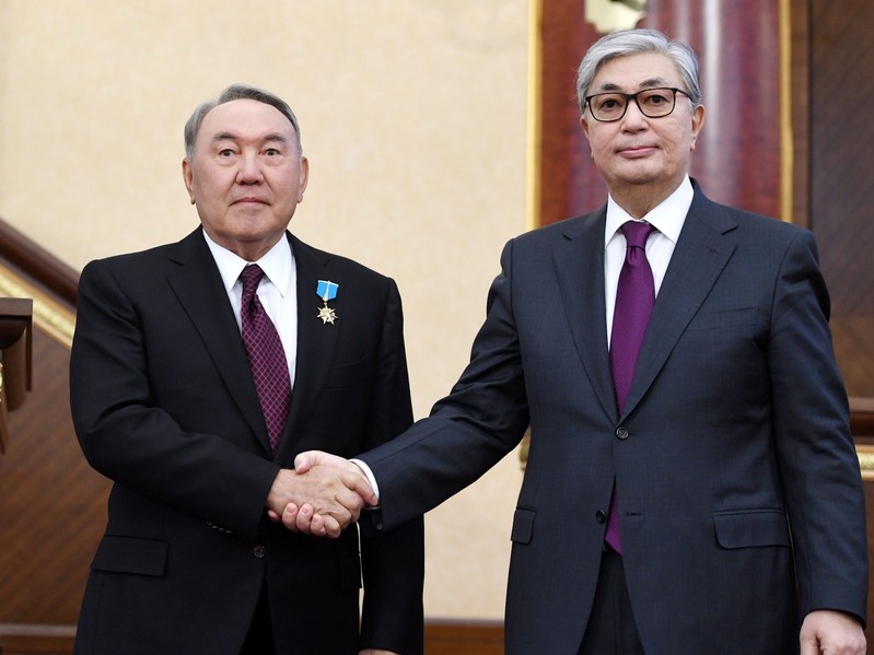 Acting President of Kazakhstan Tokayev shakes hands with his predecessor Nazarbayev during a joint session of the houses of parliament in Astana