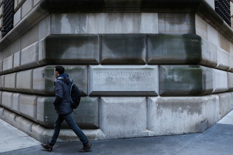 A man passes by the corner stone on the Federal Reserve Bank of New York in the financial district in New York