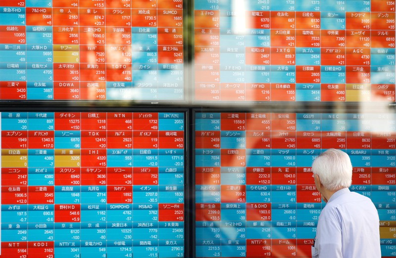 FILE PHOTO: A man looks at an electronic stock quotation board outside a brokerage in Tokyo