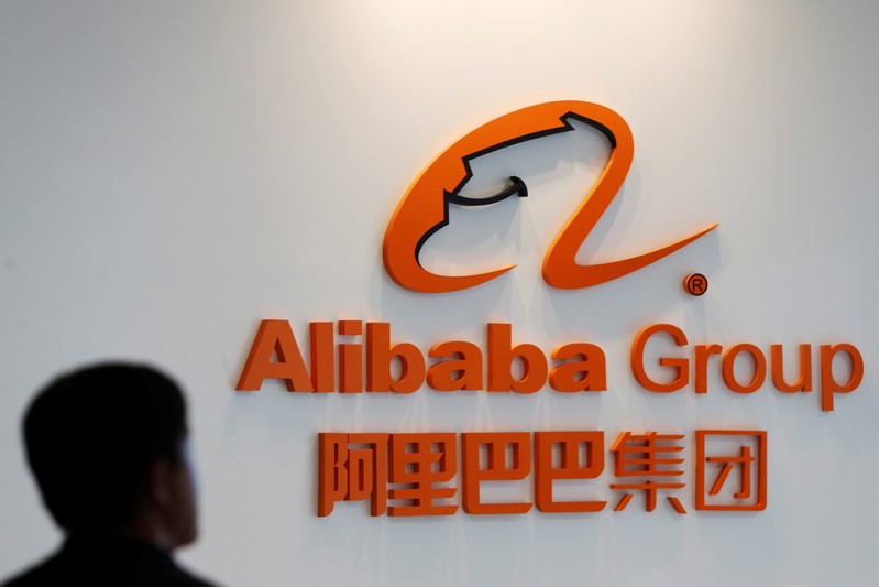 FILE PHOTO: A man stands near the logo of Alibaba Group at the company's newly-launched office in Kuala Lumpur