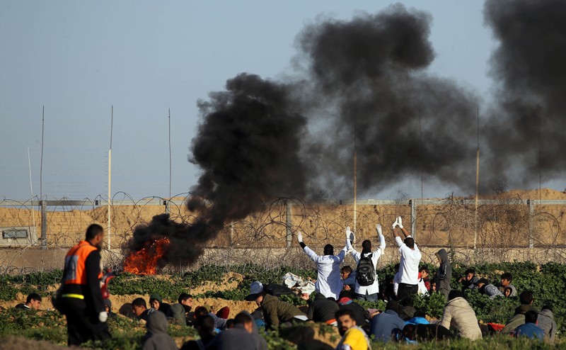 Palestinian medics raise up their hands as they try to evacuate a wounded demonstrator during protest at the Israel-Gaza border fence, in the southern Gaza Strip