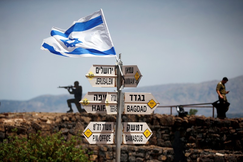 FILE PHOTO: An Israeli soldier stands next to signs pointing out distances to different cities, on Mount Bental, an observation post in the Israeli-occupied Golan Heights that overlooks the Syrian side of the Quneitra crossing