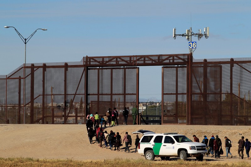 FILE PHOTO: Migrants from Central America are seen escorted by U.S. Customs and Border Protection officials after crossing the border from Mexico to surrender to the officials in El Paso, Texas, U.S., in this pictured taken from Ciudad Juarez