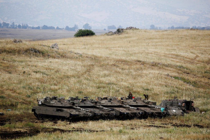 FILE PHOTO: Israeli soldiers stand on tanks near the Israeli side of the border with Syria in the Israeli-occupied Golan Heights
