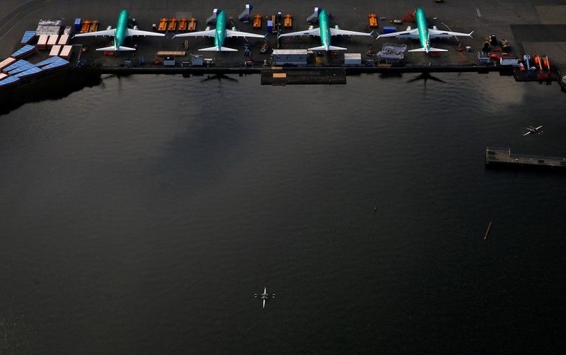 An aerial photo shows rowers on Lake Washington near a line of Boeing 737 MAX aircraft at the Boeing factory in Renton
