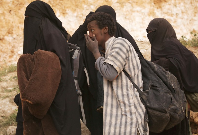 FILE PHOTO: Islamic state militant and women walk as they surrendered in the village of Baghouz, Deir Al Zor province