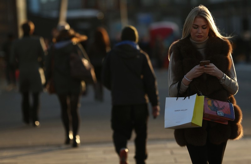 A woman checks her phone as she walks across London Bridge in London