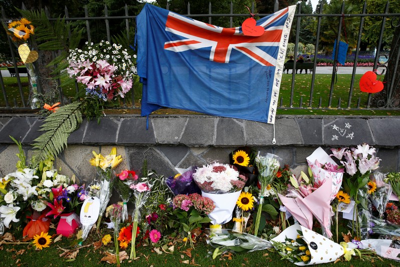Flowers and a New Zealand national flag are seen at a memorial as tributes to victims of the mosque attacks near Linwood mosque in Christchurch
