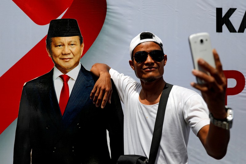 FILE PHOTO: Man takes selfie pictures with a cutout of Indonesia's presidential candidate for the upcoming election Prabowo Subianto during a campaign rally in Solo