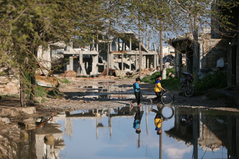 Children play near damaged houses in Kobani