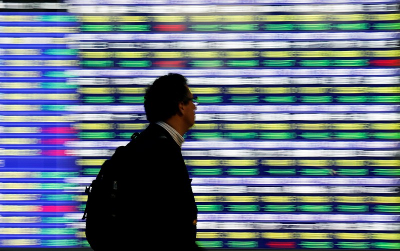FILE PHOTO: A man walks past an electronic stock quotation board outside a brokerage in Tokyo