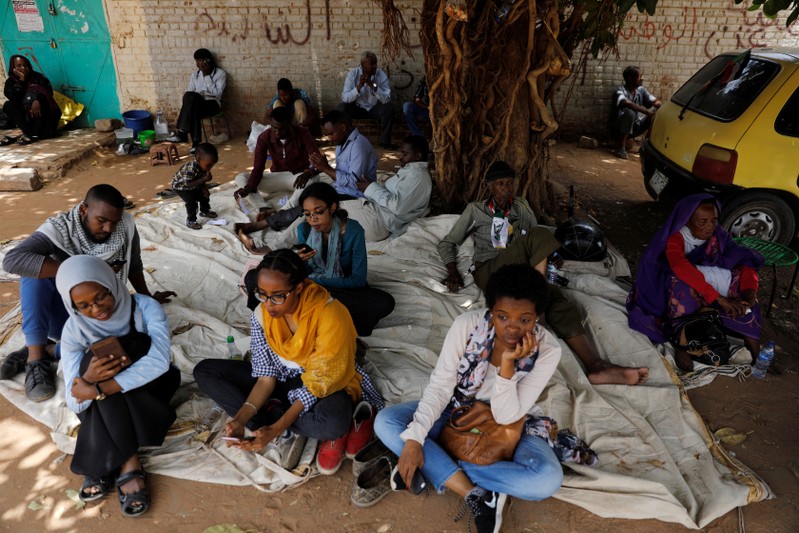 Sudanese demonstrators rest under the shadow of a tree in front of the Defence Ministry in Khartoum