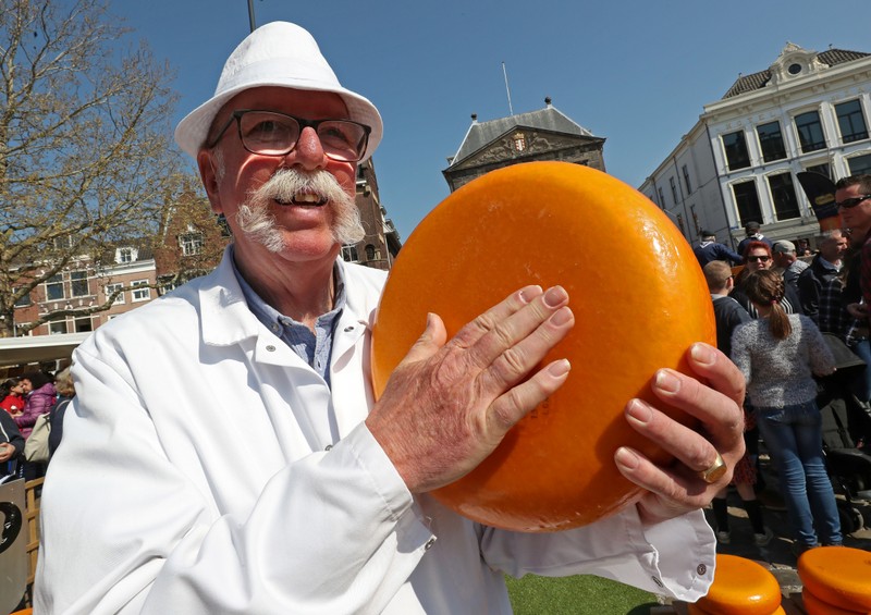 A seller holds a piece of Gouda cheese at the cheese market in Gouda