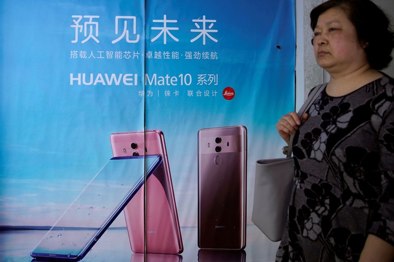 Woman walks past an advertisement on an elevator showing Huawei P30 series phones with a camera system co-developed with Leica, in Shanghai