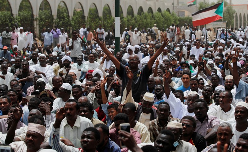 Protesters shout slogans and make victory signs after Friday prayers in front of the Defence Ministry in Khartoum