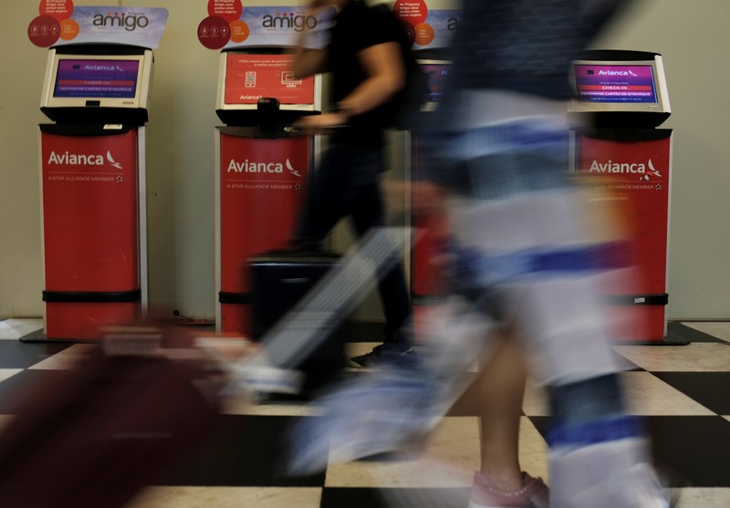 Customers walk past Avianca airline check-in machines at Congonhas airport in Sao Paulo