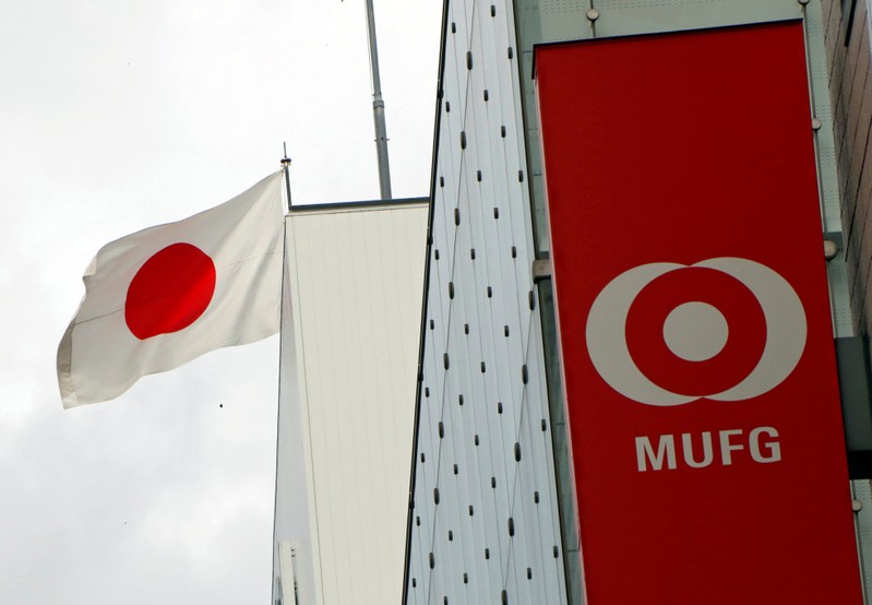 Japan's national flag is seen behind the logo of Mitsubishi UFJ Financial Group Inc (MUFG) at its bank branch in Tokyo