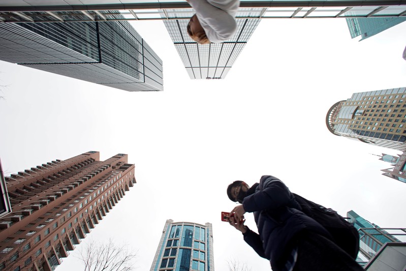 FILE PHOTO: A man checks phone at Lujiazui financial district in Pudong