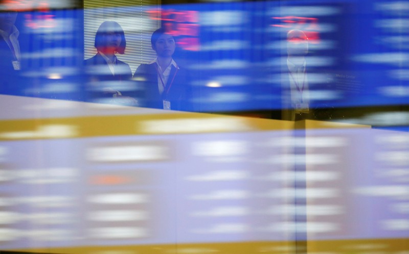 Visitors are seen as market prices are reflected in a glass window at the TSE in Tokyo