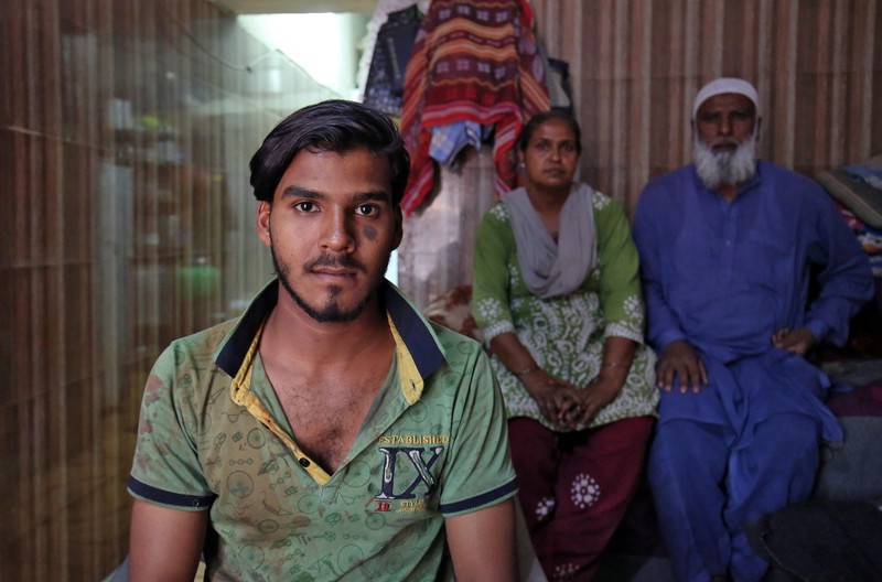 Mohammad Rafiq poses with his parents inside their house in Ahmedabad