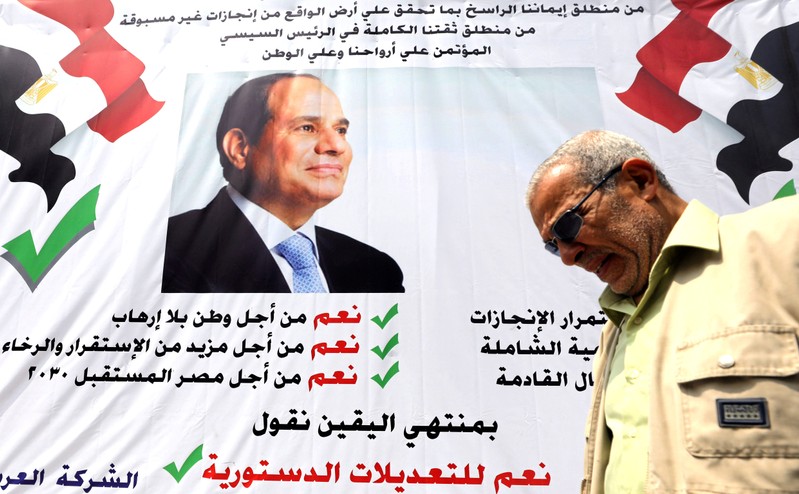 FILE PHOTO: A man walks in front of a banner reading,